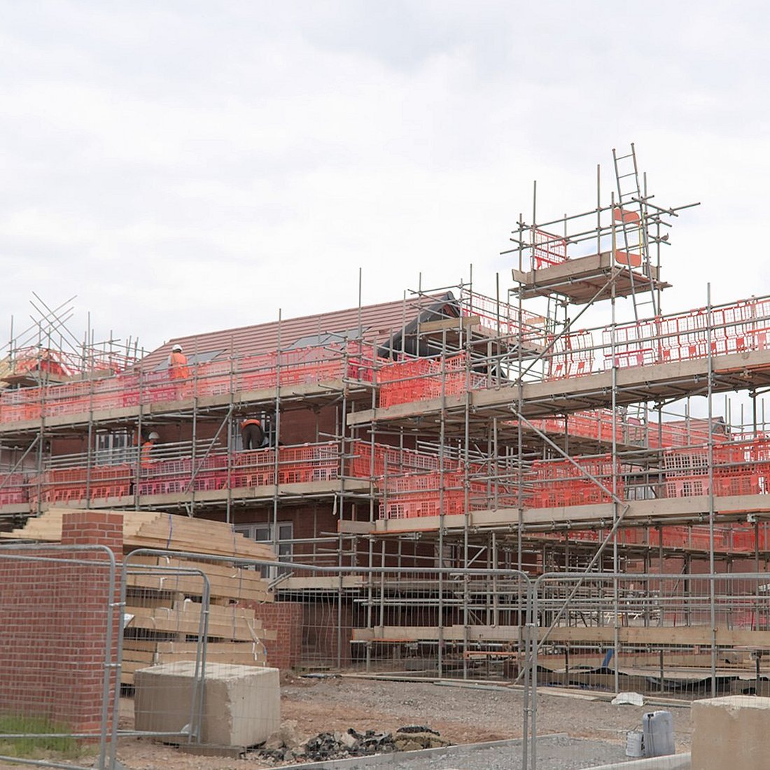 Scaffold on a brick house, with a stack of timber